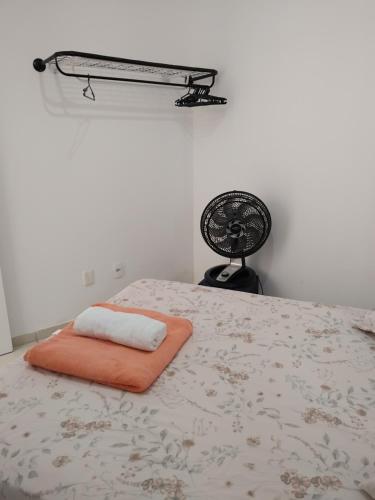 a bed with an orange pillow and a fan at EM CASA in Palhoça