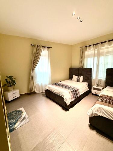 a bedroom with two beds and two windows at comfort homes in Kampala