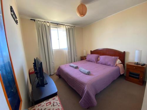 a bedroom with a purple bed and a television at Condominio María Teresa in Quintero