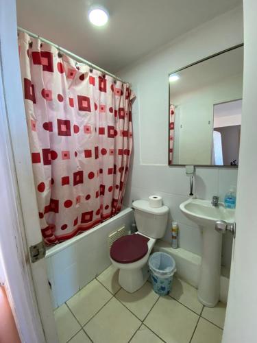 a bathroom with a toilet and a sink and a shower curtain at Condominio María Teresa in Quintero