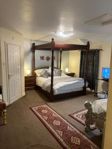 a bedroom with a canopy bed and a tv at Lynebank House Hotel, Bed & Breakfast in Carlisle