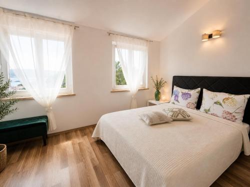 a bedroom with a large bed and two windows at Apartments Casa al Vento in Donja Klada