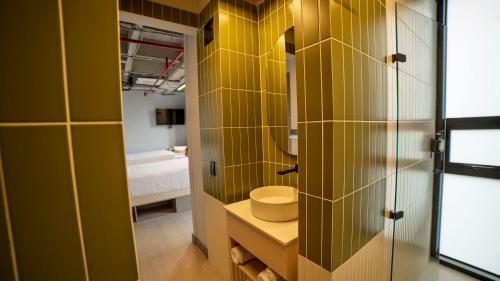 a bathroom with yellow tile walls and a toilet at CITIO Hotel - Laureles in Medellín