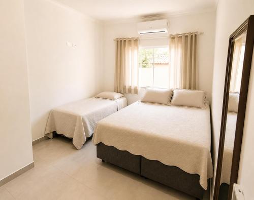 a bedroom with two beds and a window at Casa da Cle, 2 quartos com ar condicionado, 600m da praia in Itapoa