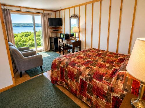 a bedroom with a bed and a desk with a television at Baddeck Inn in Baddeck