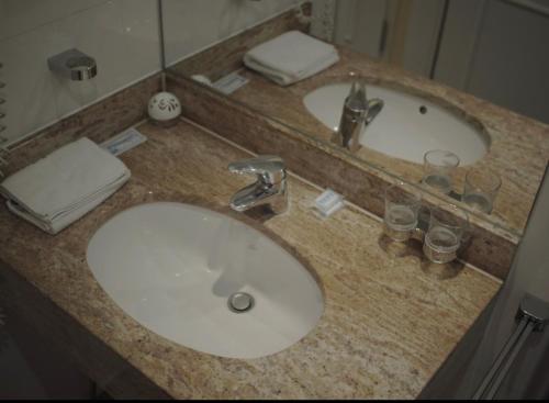 a bathroom counter with a sink and two mirrors at Hotel La Strada & Sultan in Murnau am Staffelsee