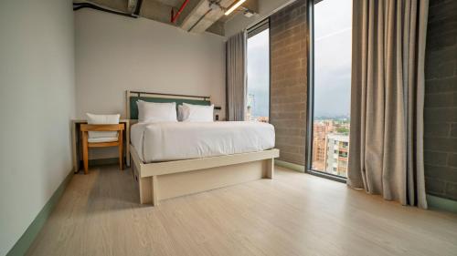a bedroom with a bed and a large window at CITIO Hotel - Laureles in Medellín