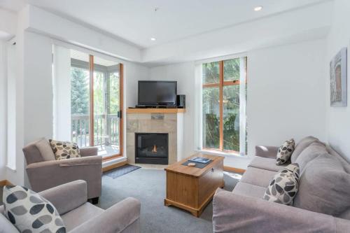 a living room with two couches and a fireplace at Bright and Clean, Walk Everywhere, Shared Pool and Hot Tub in Whistler