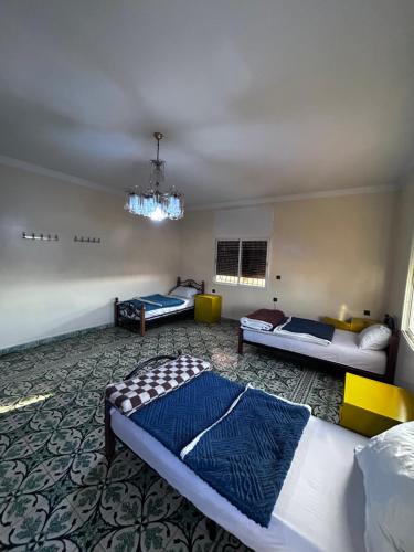 a bedroom with two beds and a chandelier at Tabriquet urban shared room in Salé