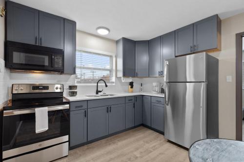 a kitchen with blue cabinets and a stainless steel refrigerator at Private 1BR for Two on Morganford in Saint Louis