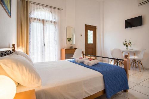a bedroom with a large white bed and a table at Natsios Apartments in Vlachopoulátika