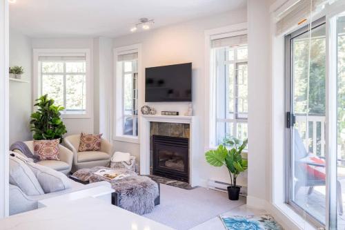 a living room with a fireplace and a tv at Panoramic Views from this gorgeous 2 Bed Property - Village Location in Whistler