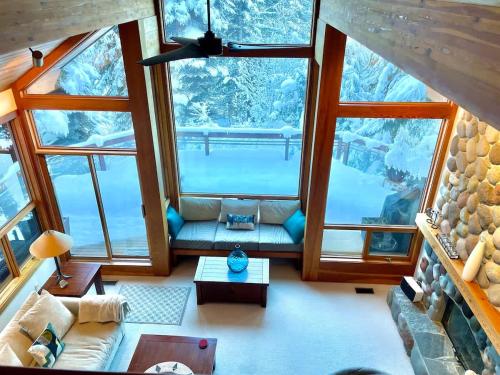 a living room with large windows in a tree house at Luxury 5 Bedroom Blueberry Chalet in Whistler