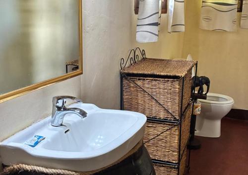 a bathroom with a sink and a toilet and a mirror at Kilimanjaro Lodge - MCF in Moshi