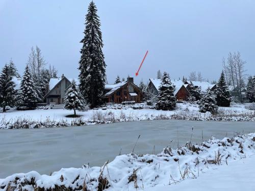 a house in the snow with a frozen pond at 8140 Nicklaus North in Whistler