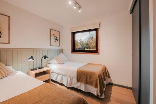 a hotel room with two beds and a window at Cabañas Parque Futangue in Lago Ranco