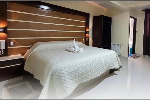 a bedroom with a large white bed with a wooden headboard at Hostal Face in La Paz