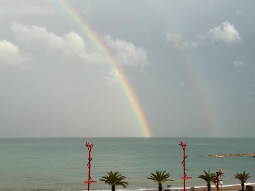 a rainbow over the beach with palm trees and the ocean at MAR Apartamentos in Vinarós