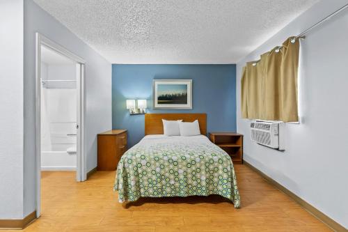 a bedroom with a bed and a blue wall at HomeTowne Studios by Red Roof Orlando South in Orlando
