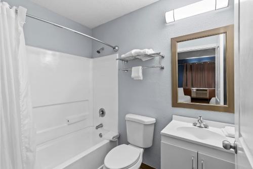 a bathroom with a toilet and a sink and a mirror at HomeTowne Studios by Red Roof Orlando South in Orlando