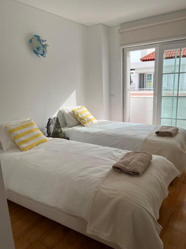 two beds in a white room with a window at Ria Seahouse Cabanas de Tavira in Tavira