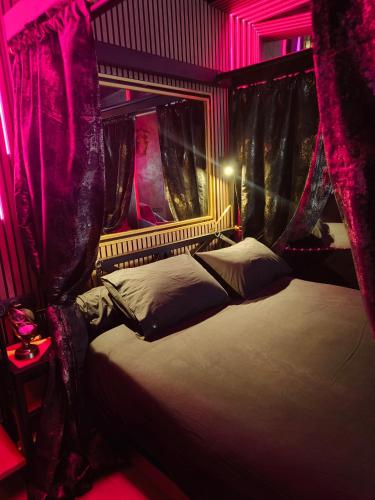 a bedroom with a bed with red lighting and drapes at Luxuria - Jacuzzi et Hammam in Le Cannet
