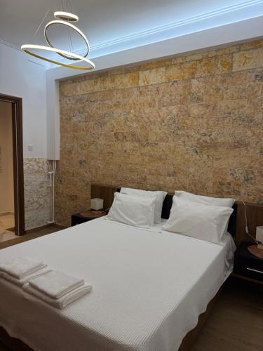 a bedroom with a large white bed with a brick wall at Aphrodite Apartment in Athens