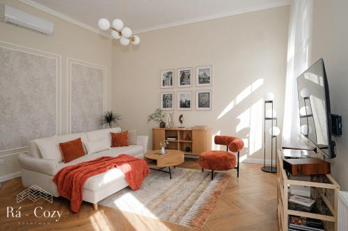 a living room with a white couch and a chair at Rá-Cozy in Pécs