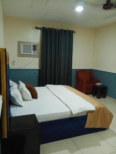 a bedroom with a large bed and a chair at OUR HILLs HOTELs AND SUITES in Ekoro
