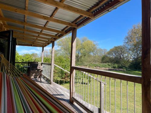 a hammock on a deck with a view at Zambezi Cabin in Halesworth
