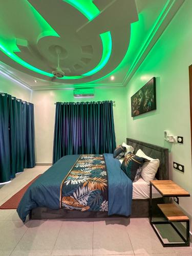 a bedroom with a bed with a green ceiling at Les Résidences AKATA-Appartement HOUÈ in Abomey-Calavi