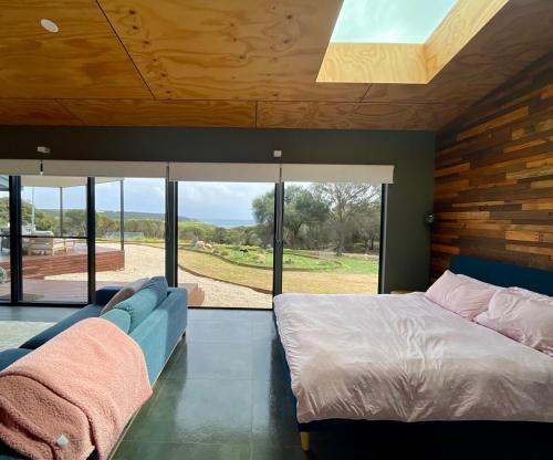 a bedroom with a bed and a couch and windows at Stokes Bay Cliffs Kangaroo Island in Stokes Bay