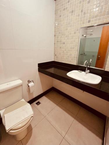 a bathroom with a toilet and a sink and a mirror at Hotel Mata da Praia in Vitória