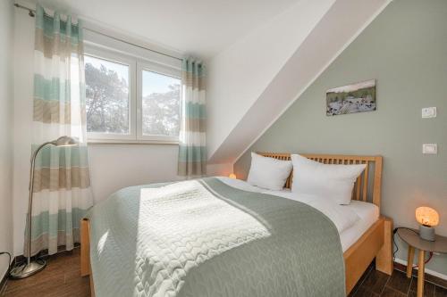 a bedroom with a bed and a window at FeWo Dünengrün in Trassenheide