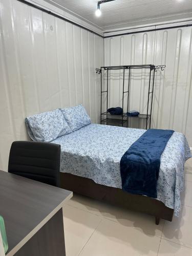 a bedroom with a bed with a blue blanket on it at Casa Container Completa e Privativa em Sombrio-SC in Sombrio