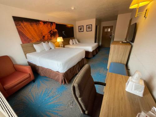 ein Hotelzimmer mit zwei Betten, einem Schreibtisch und einem Stuhl in der Unterkunft Days Inn by Wyndham Capitol Reef in Torrey