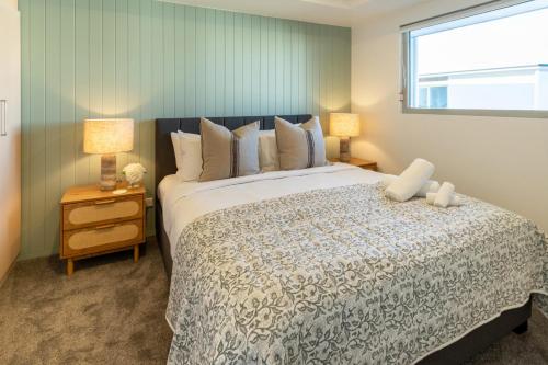 a bedroom with a large bed and a window at Waves & Wellness - Spa Pool and Parking in Christchurch