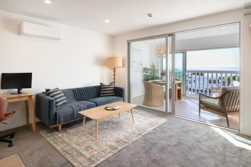 a living room with a couch and a table at Waves & Wellness - Spa Pool and Parking in Christchurch