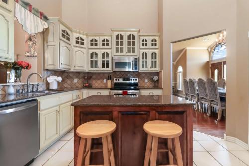 a kitchen with white cabinets and wooden stools at Casa Oasis Extra Large home centrally located in Springdale