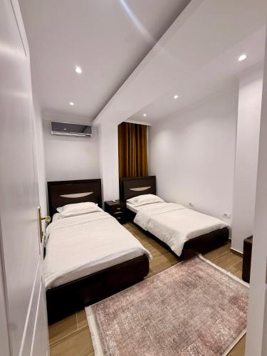 two beds in a room with two rugs at Aisha Apartment in Berat