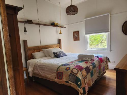 a bedroom with a bed with a comforter and a window at Tarndwarncoort Homestead in Warncoort