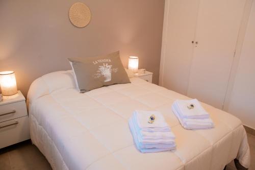 a bedroom with a white bed with towels on it at Epoca in Tandil