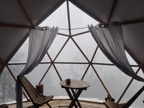 a room with two chairs and a table in front of a window at Glamping Entre las Nubes in Mineral del Monte
