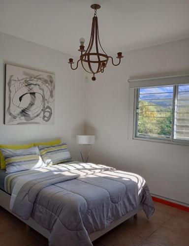 a bedroom with a bed and a chandelier and a window at Loft Las Acacias in Potrero de los Funes