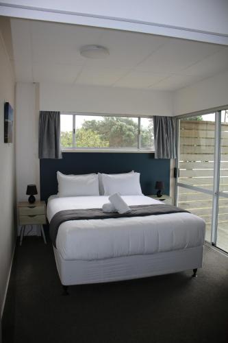 a bedroom with a white bed with a large window at Pakiri Beach Holiday Park in Pakiri