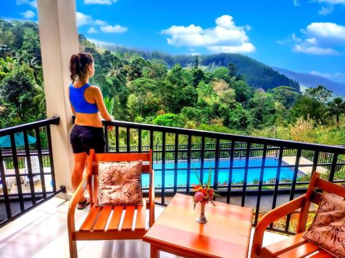 a woman standing on a balcony looking out at a pool at Grand Hills in Kandy