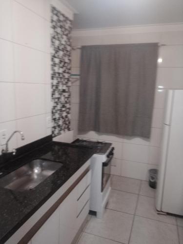 a small kitchen with a sink and a refrigerator at Ap Simples arc, bem localizado confortável e aconchegante, 2 quartos in Araçatuba