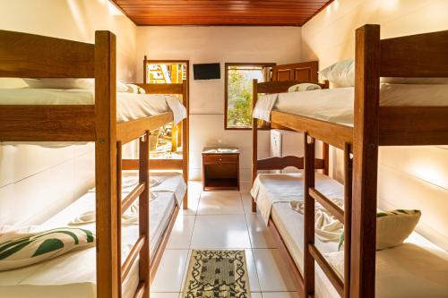 a room with three bunk beds in a house at Tapirandú Pousada in Morro de São Paulo