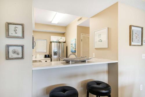a kitchen with a counter and two stools at Beachside Resort Condo with Pools and Tennis in Destin