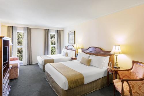 a hotel room with two beds and a television at Canterbury International Hotel in Forest Hill